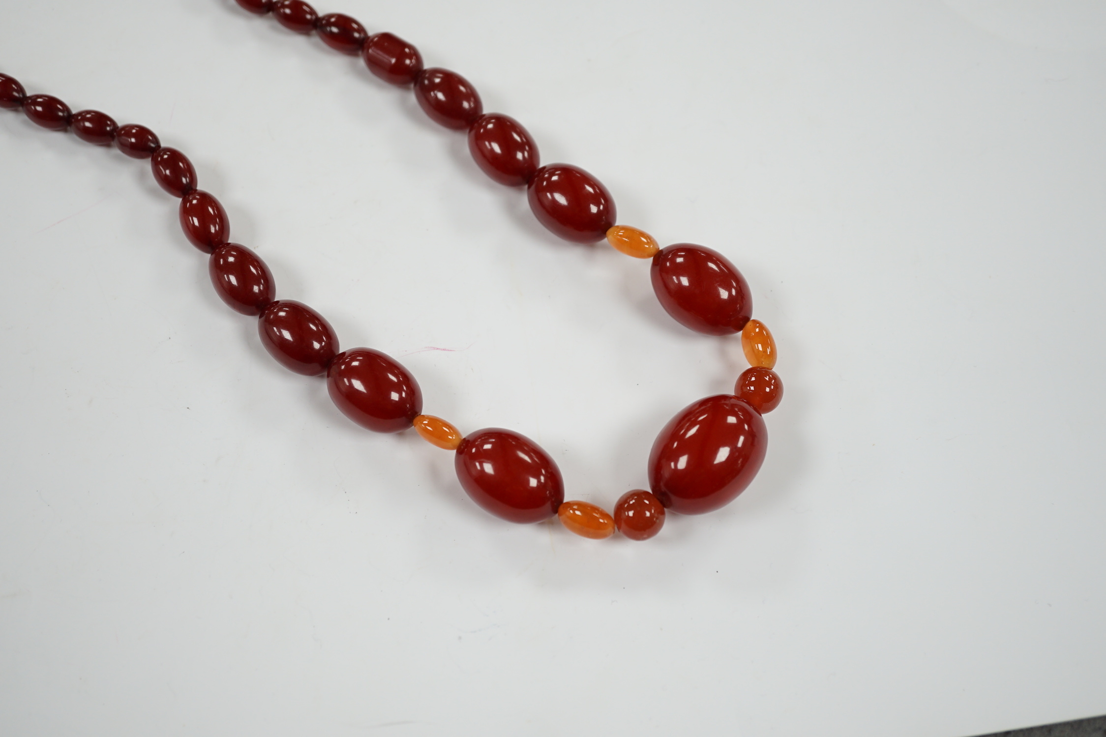 A single strand graduated simulated cherry amber bead necklace, with four simulated orange amber beads, 66cm, gross weight 84 grams.
